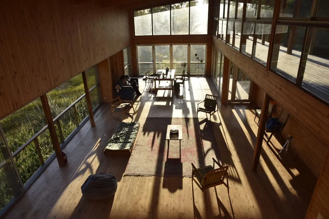 El interior del Galpón, de madera, con sillas y ventanales por donde entra el sol de la tarde